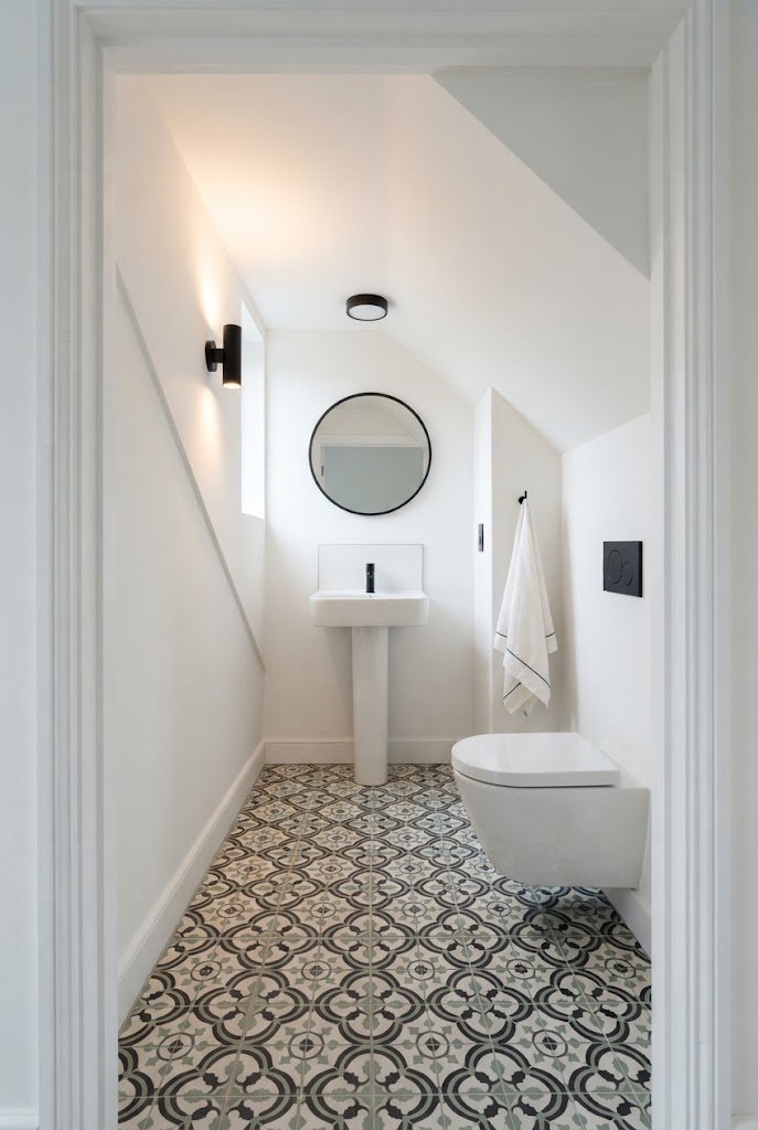 Patterned black and white floor tile in a small under stairs bathroom